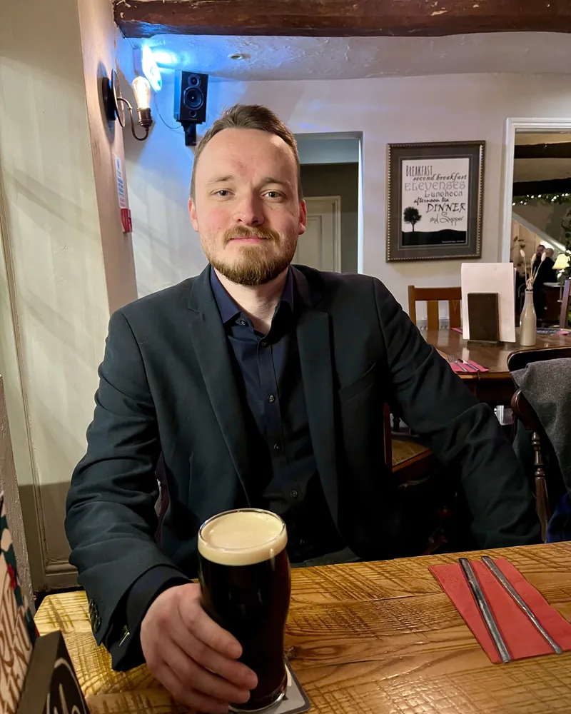 Anthony at a wooden pub table with a pint of stout