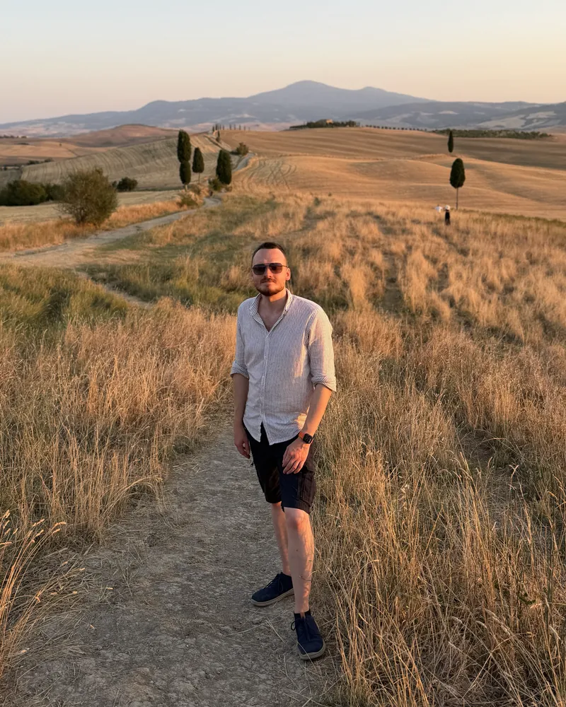 Anthony on a country path through golden fields and cypress trees in Tuscany
