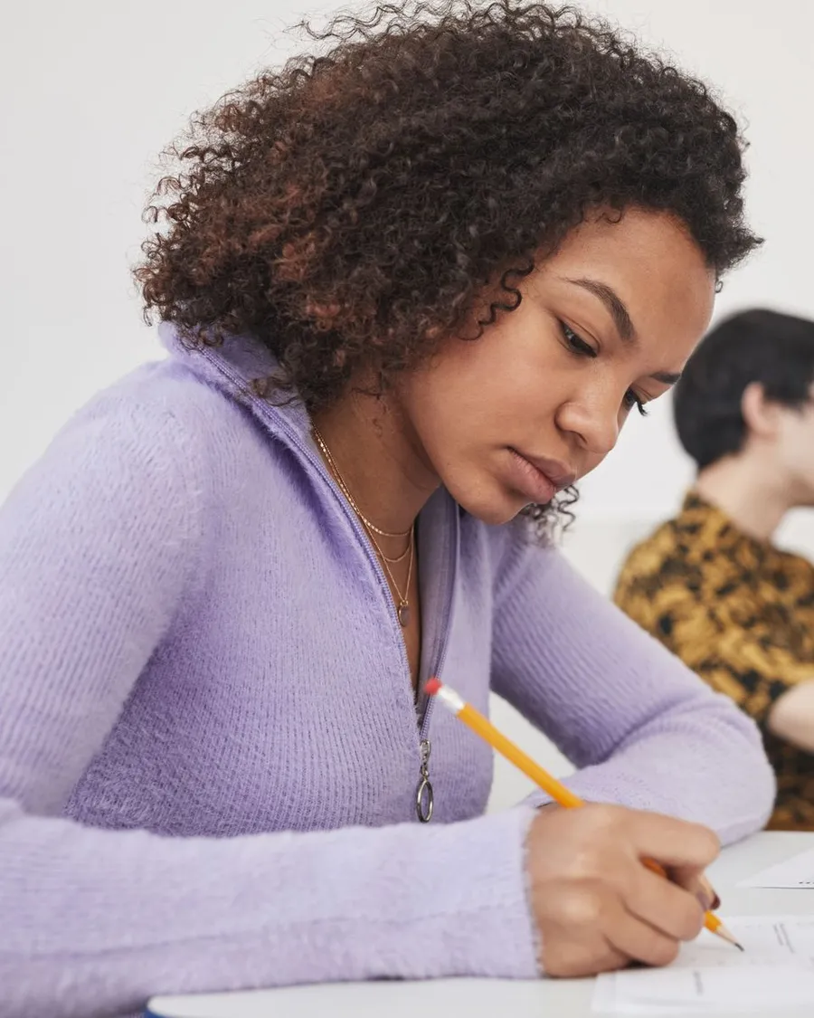 A student concentrating as she writes her exam answers